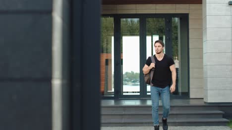 Casual-man-going-down-stairs-building-with-backpack.-Portrait-of-male-employee