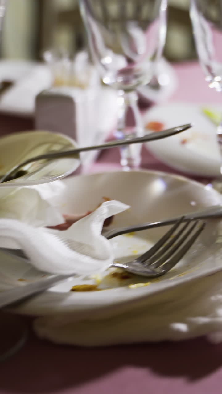 Empty plate after eating food. With fork and knife on it. Wasted food on festive table after dinner party Vertical video
