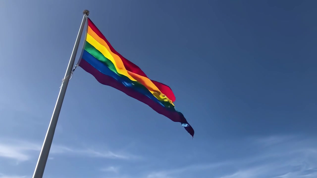 Drapeau arc-en-ciel de la Fierté flottant sur un ciel bleu clair
