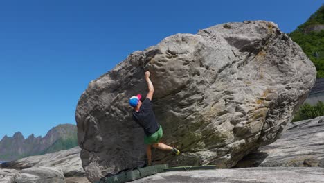 joven boulder en roca en senja en noruega con buen clima y montañas en el fondo