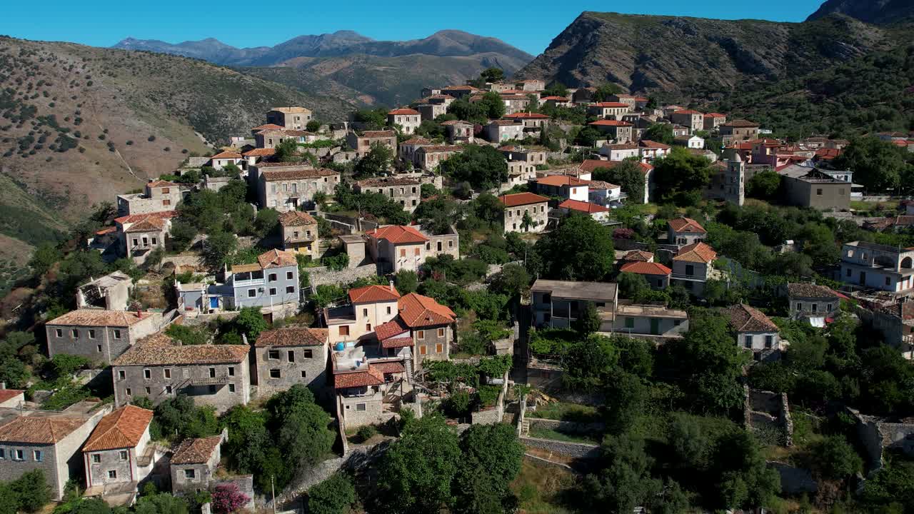 casas de piedra alrededor de la iglesia con torre del campanario en el pueblo panorámico de qeparo en la costa albanesa, construidas en una colina rocosa frente al sol