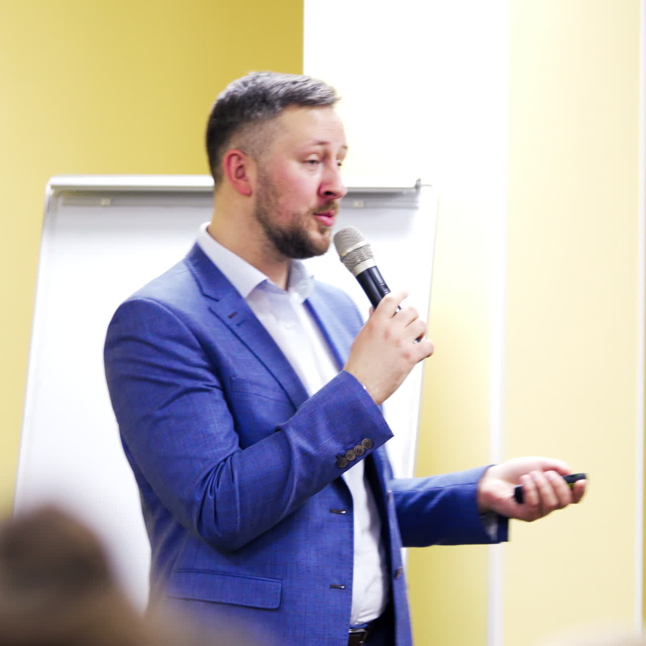 Half-length portrait of a businessman talking to the microphone during the business forum. Handsome male speaking at conference indoors.