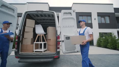 two young workers of removal company are loading boxes and furniture into a minibus