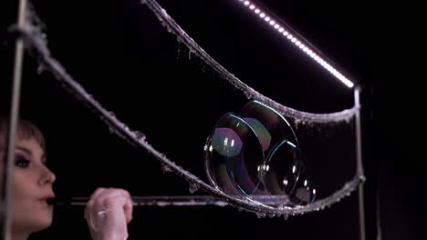 Close-up-Woman-does-tricks-with-soap-bubbles-She-blows-few-bubbles-in-the-form-of-pyramid