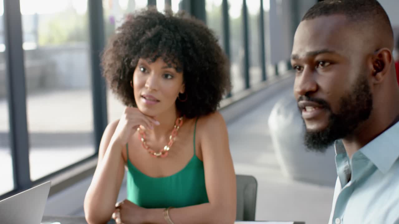 Team of diverse colleagues discussing while sitting together at office