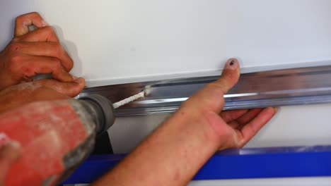 el maestro aprieta los tornillos con un destornillador eléctrico en cámara lenta