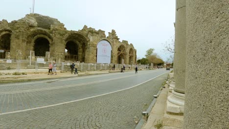 Antike-Stadt-Side---Touristen-Gehen-Vor-Den-Ruinen-Des-Antiken-Theaters-In-Side,-Türkei