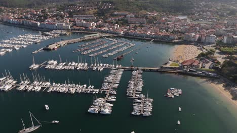 aerial view of baiona marina with boats lined up in the water, bordered by the village