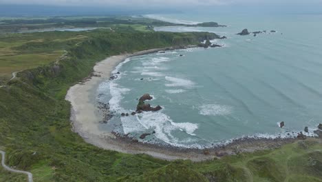 aerial landscape view of tasman sea and waves rolling into shoreline in the remote wilderness of cape foulwind on west coast, south island of new zealand aotearoa