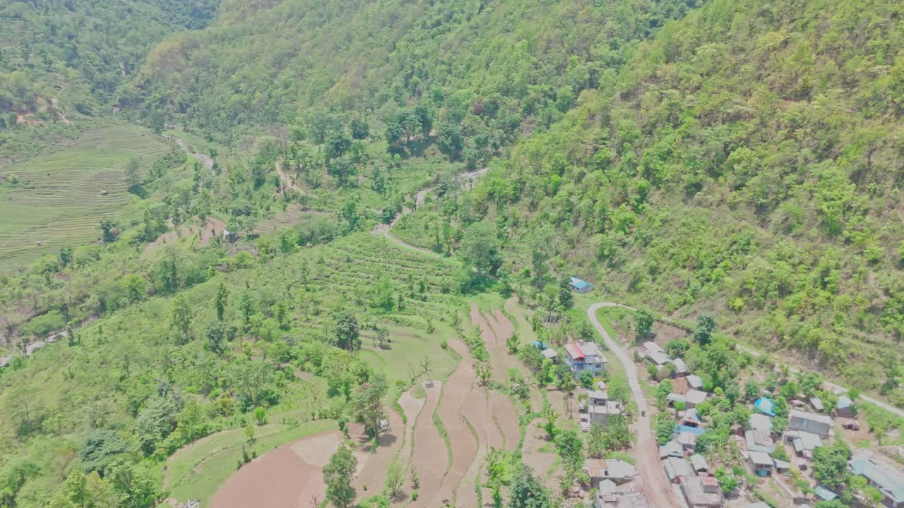 A cable car glides over green hills and a quiet village, capturing a peaceful rural landscape from above. Ideal for themes of travel, nature, infrastructure, and mountain community life