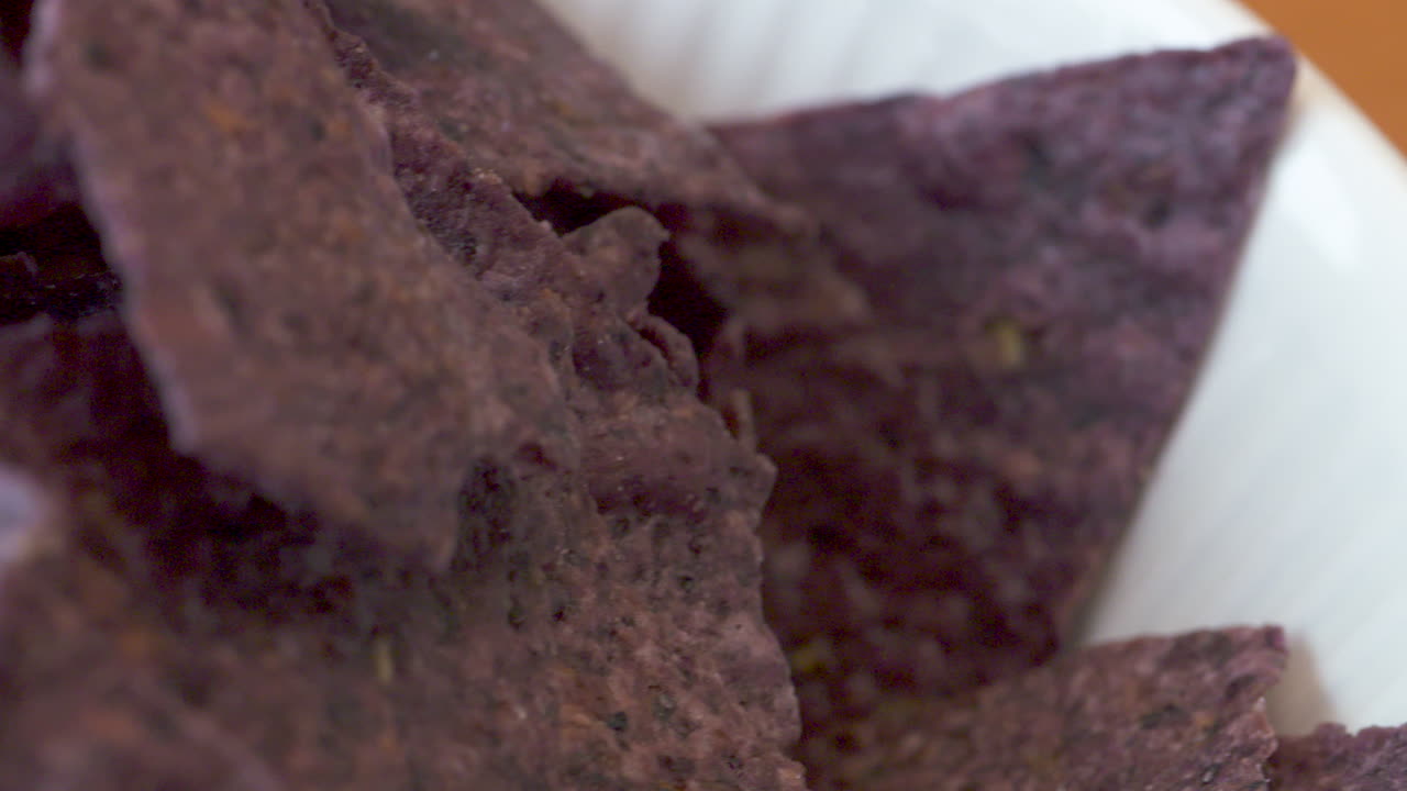 Macro slide across a bowl of delicious, crunchy, blue nachos