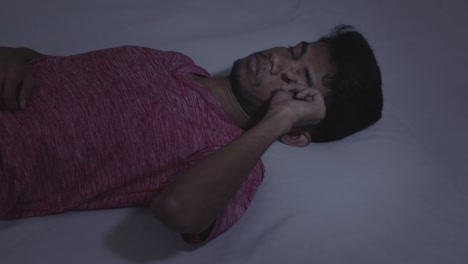 concept of a sleeping disorder or insomnia, young indian male adult trying to sleeping during the night at home