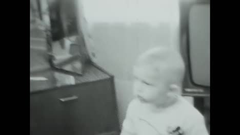 Little Boy Standing in Living Room Next to TV in USSR. CIRCA USSR 1970: A young boy stands next to a television in a living room, capturing a moment of daily life in the Soviet Union during the era of communism.