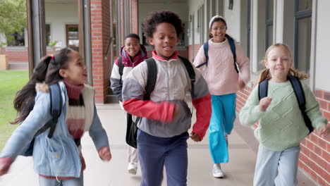 group of diverse school children running down school hallway