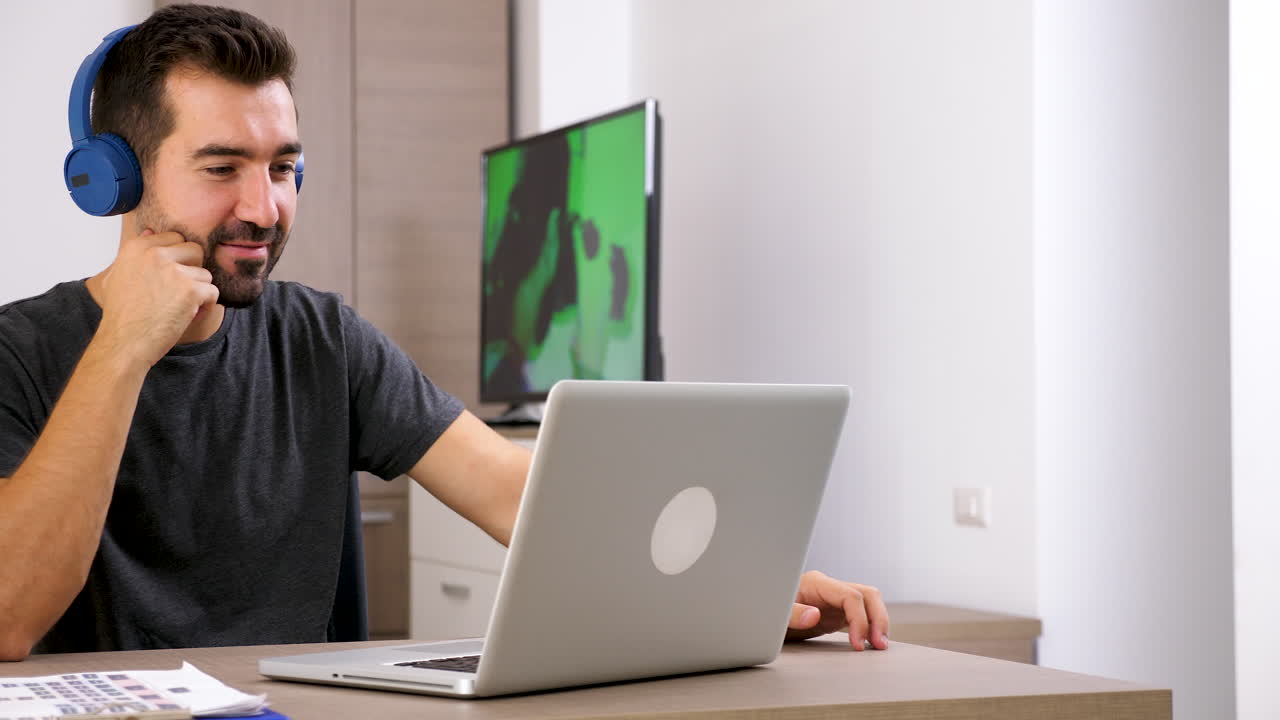 Man using laptop with headphones at home office