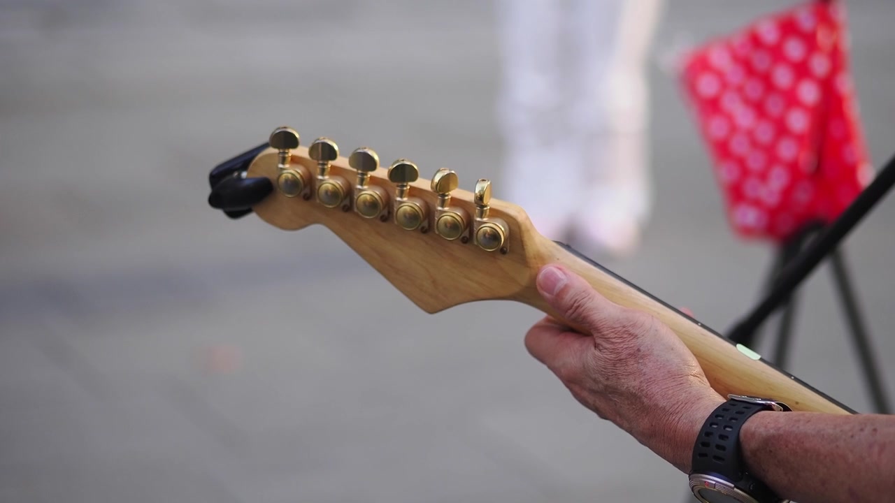 Musicista che tiene il manico di una chitarra elettrica all'aperto