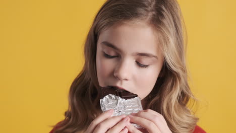 teenage caucasian girl eating chocolate bar and enjoying.