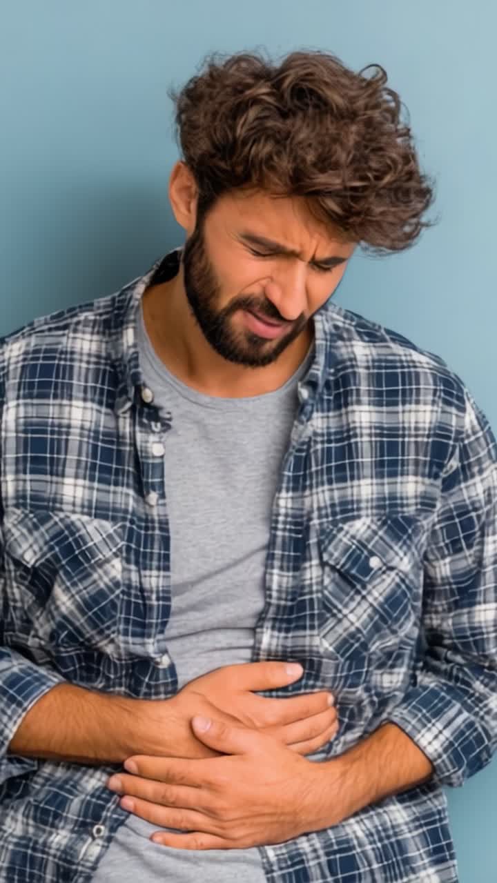Espressione di disagio: un uomo in abiti casual mostra segni di dolore addominale, evidenziando l'impatto fisico ed emotivo dei problemi di salute.