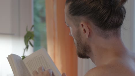 the man is reading a book, and the camera is zoomed in to capture the close-up shot