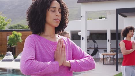 happy group of diverse friends doing yoga in garden, meditating