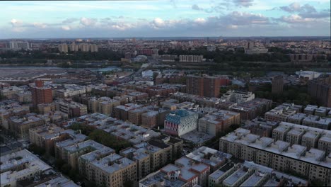 Inmersión-Aérea-En-El-Barrio-De-Inwood-En-La-Ciudad-De-Alta-Manhattan-Nueva-York-A-La-Hora-Dorada-Con-Nubes-Dramáticas