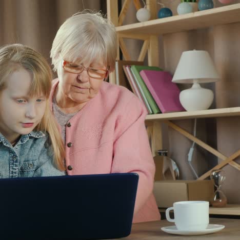 Eine-ältere-Dame-Und-Ein-Mädchen-Benutzen-Gemeinsam-Einen-Laptop-Im-Kinderzimmer