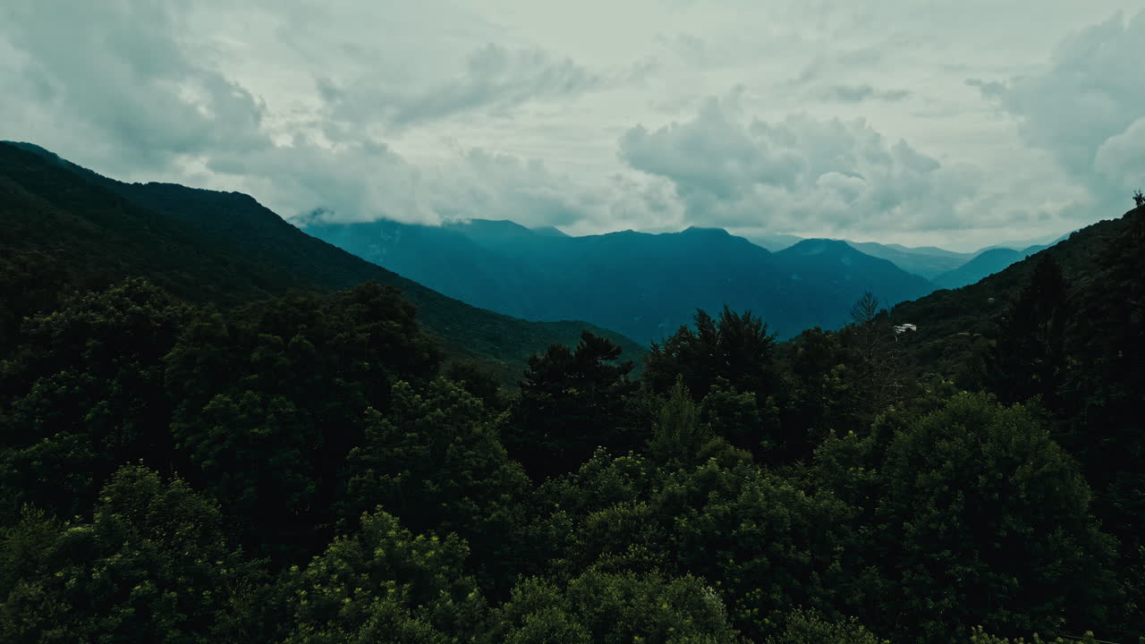 drone aéreo disparado en los alpes italianos europa central de una cordillera con un cielo nublado y un bosque en primer plano en un día nublado de mal humor