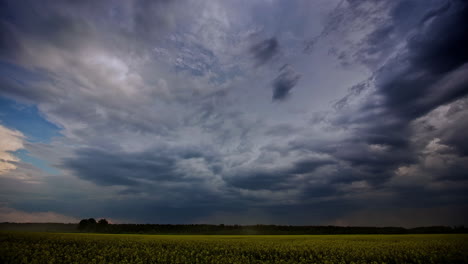 Dark,-stormy-clouds-flow-in-over-an-endless-farmland-field-of-rapeseed---cloudscape-time-lapse