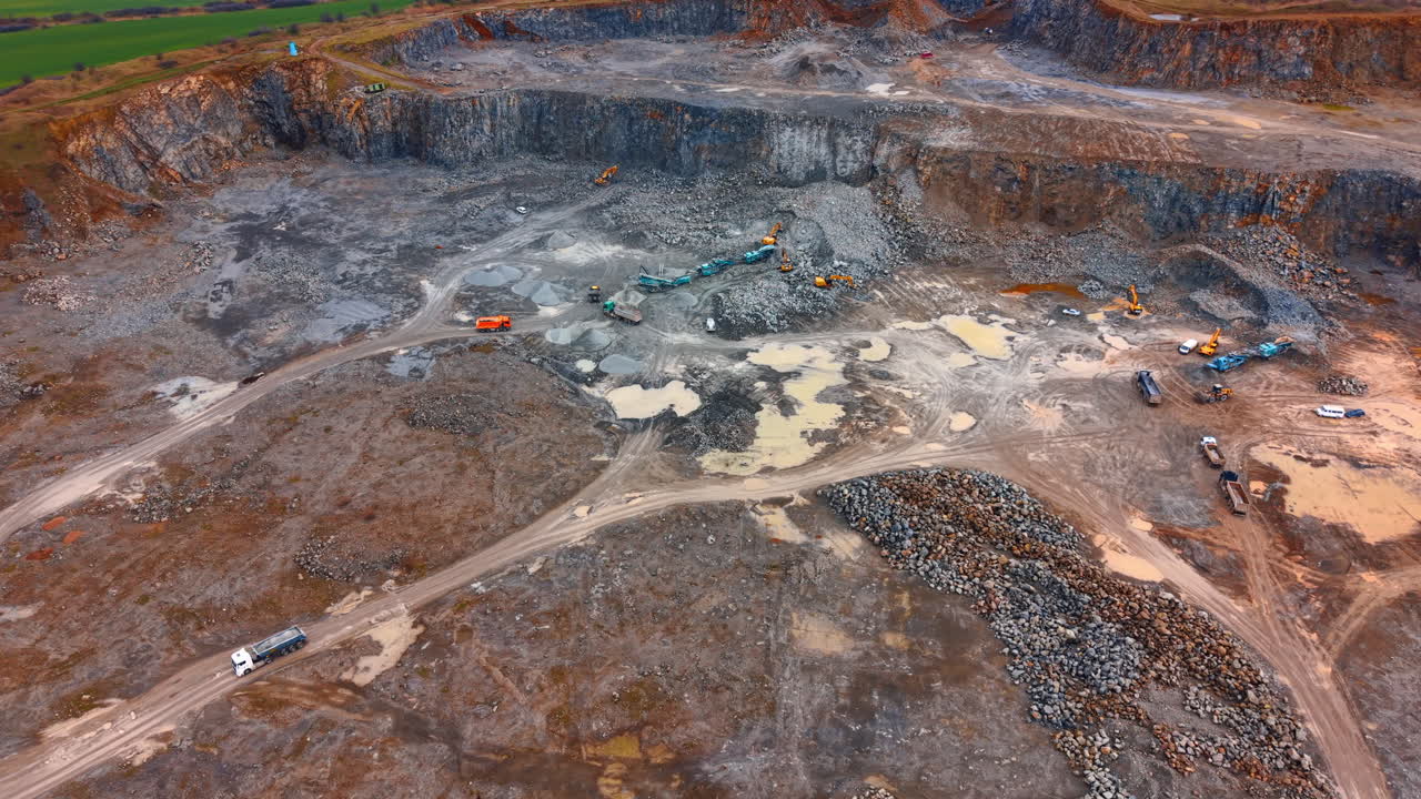 Construction work in a large quarry site. Workers and machinery operate in a large quarry with raw materials being extracted and transported across the area