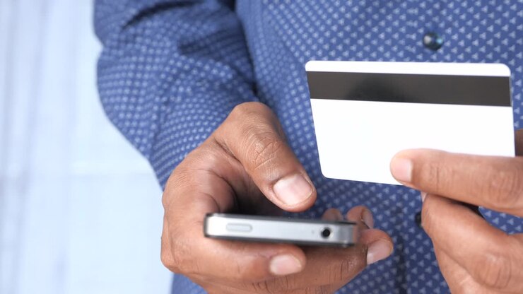 Person using a mobile phone and credit card for online payment