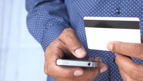 persona que utiliza un teléfono móvil y una tarjeta de crédito para el pago en línea