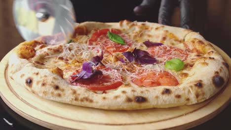 chef cuts freshly made pizza with round cutter