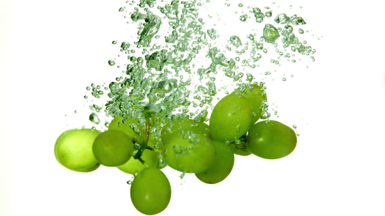 uvas que caen en el agua sobre un fondo blanco