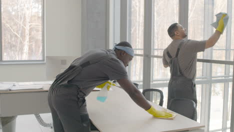 and arabic cleaning man cleaning the window panes and a desk inside an office