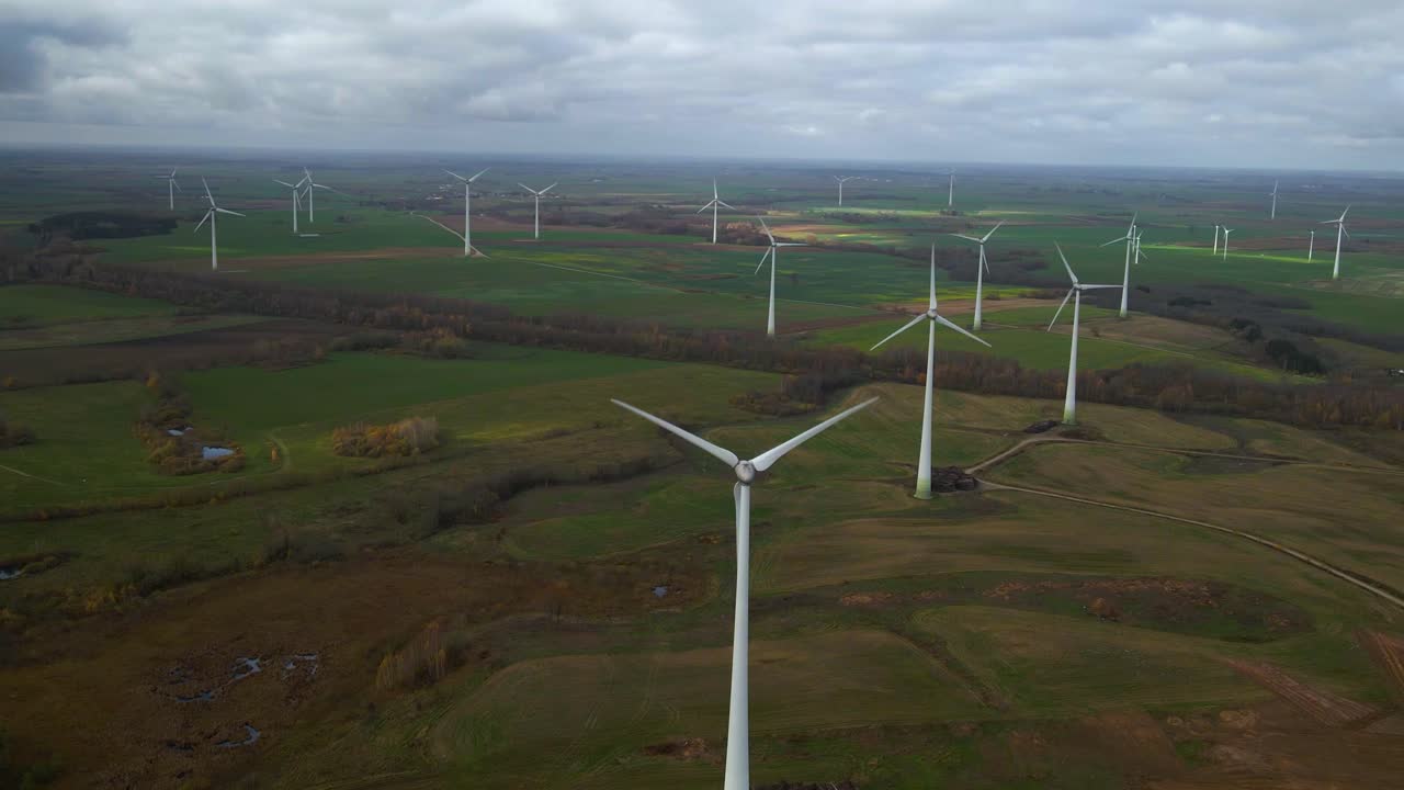 Aerial shot of group rotating windmills in wind farm for renewable electric power production in a wide rural area