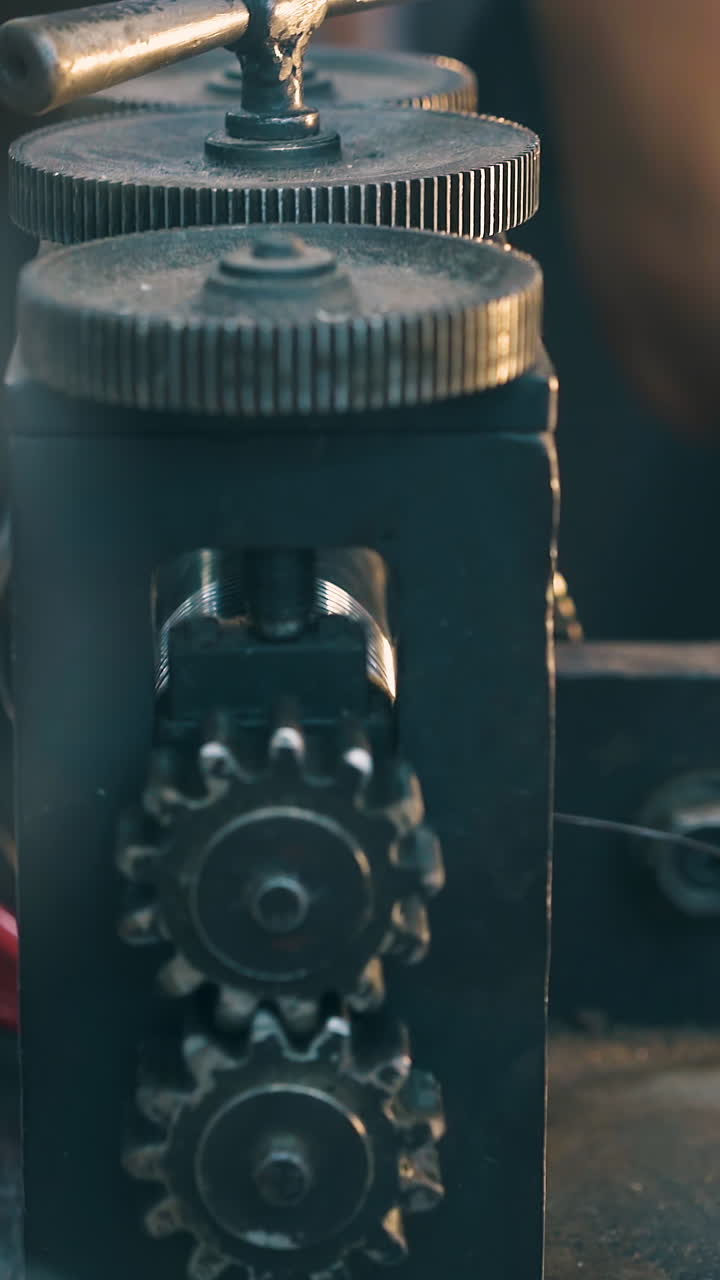 CU: skilled jeweler forge-rolls long white gold wire with special machine tool on table at workplace close view