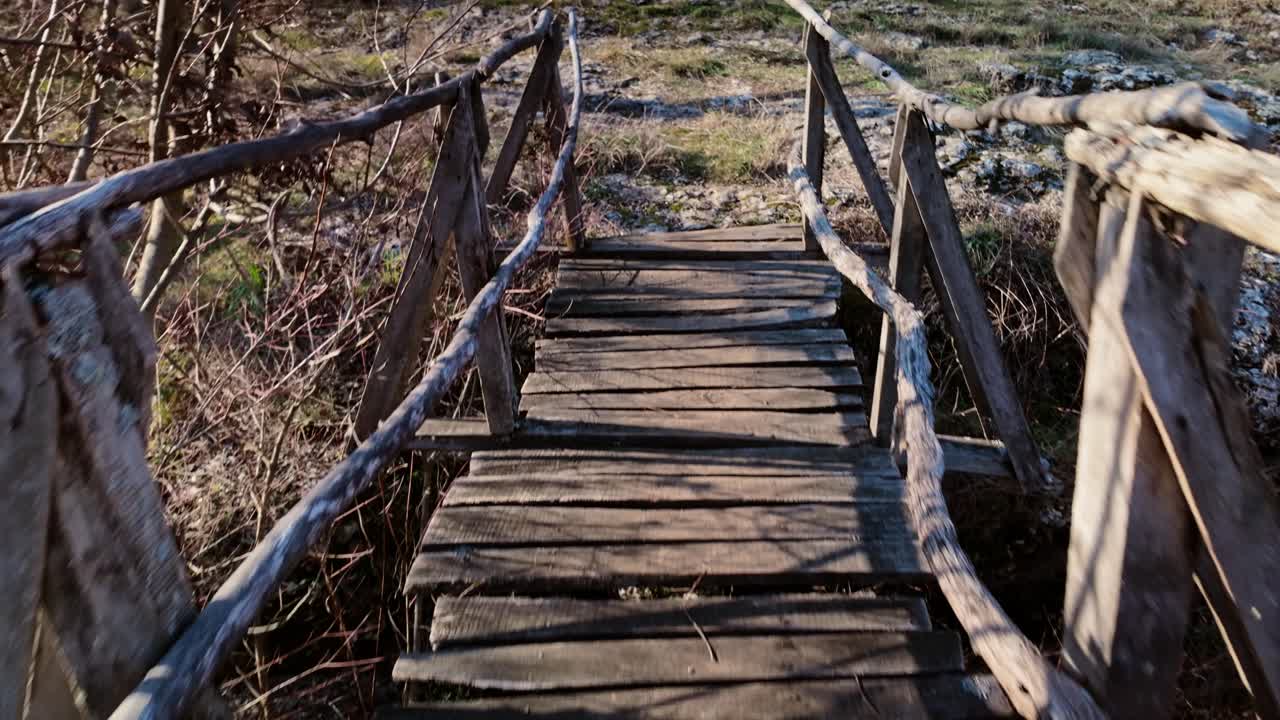 POV crossing an aged insecure wooden footbridge on hike trail