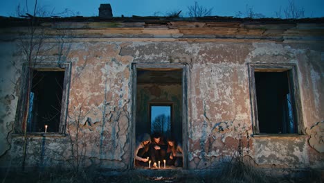 an eerie gathering amidst the decay: individuals engaged in a mysterious ritual with candles in a derelict house at dusk