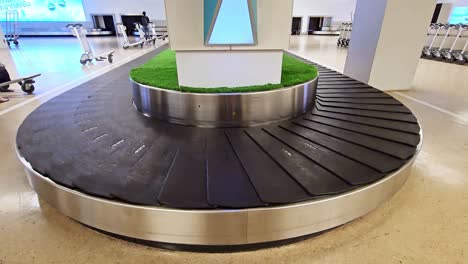 several bags and black suitcases slide on the luggage carousel, baggage claim hall of a modern airport