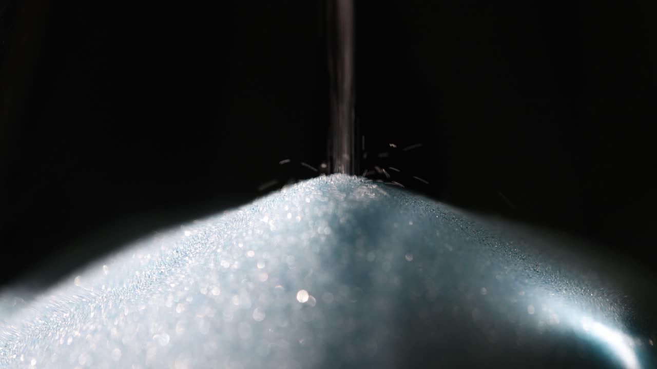Close-up of blue sand flowing through an hourglass