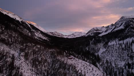 sunset drone view of a snow covered mountain valley during golden hour