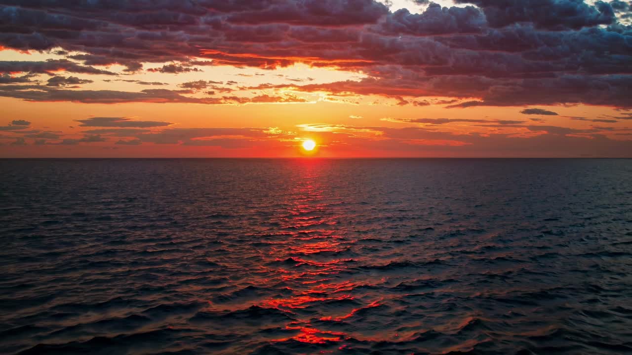 A serene ocean sunset video captured from a low angle, showcasing vibrant colors and dramatic