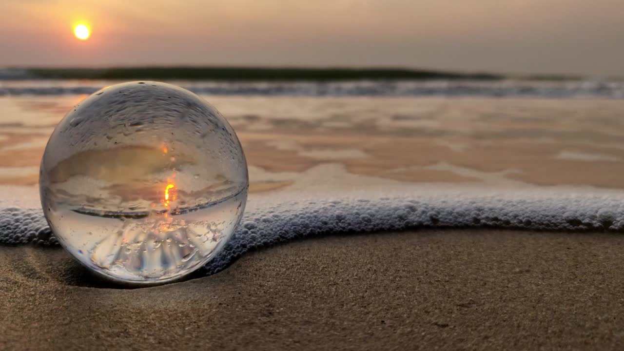 an early morning sunrise shot with a crystal ball. inverted reflection shot of the sunrise with ambient waves and wind sounds