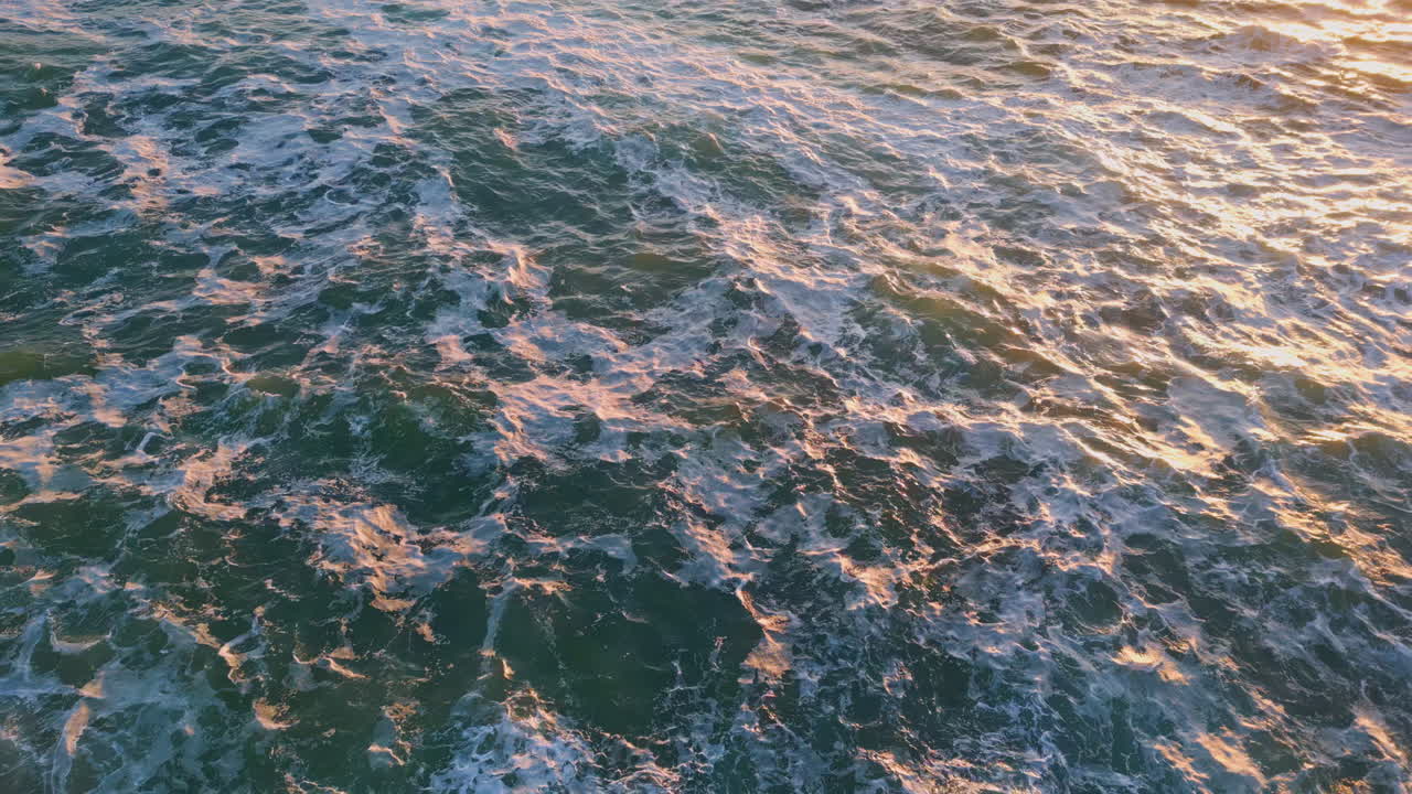 дронный вид грубой поверхности океанской воды при золотом свете заката. высокая прибрежная скала