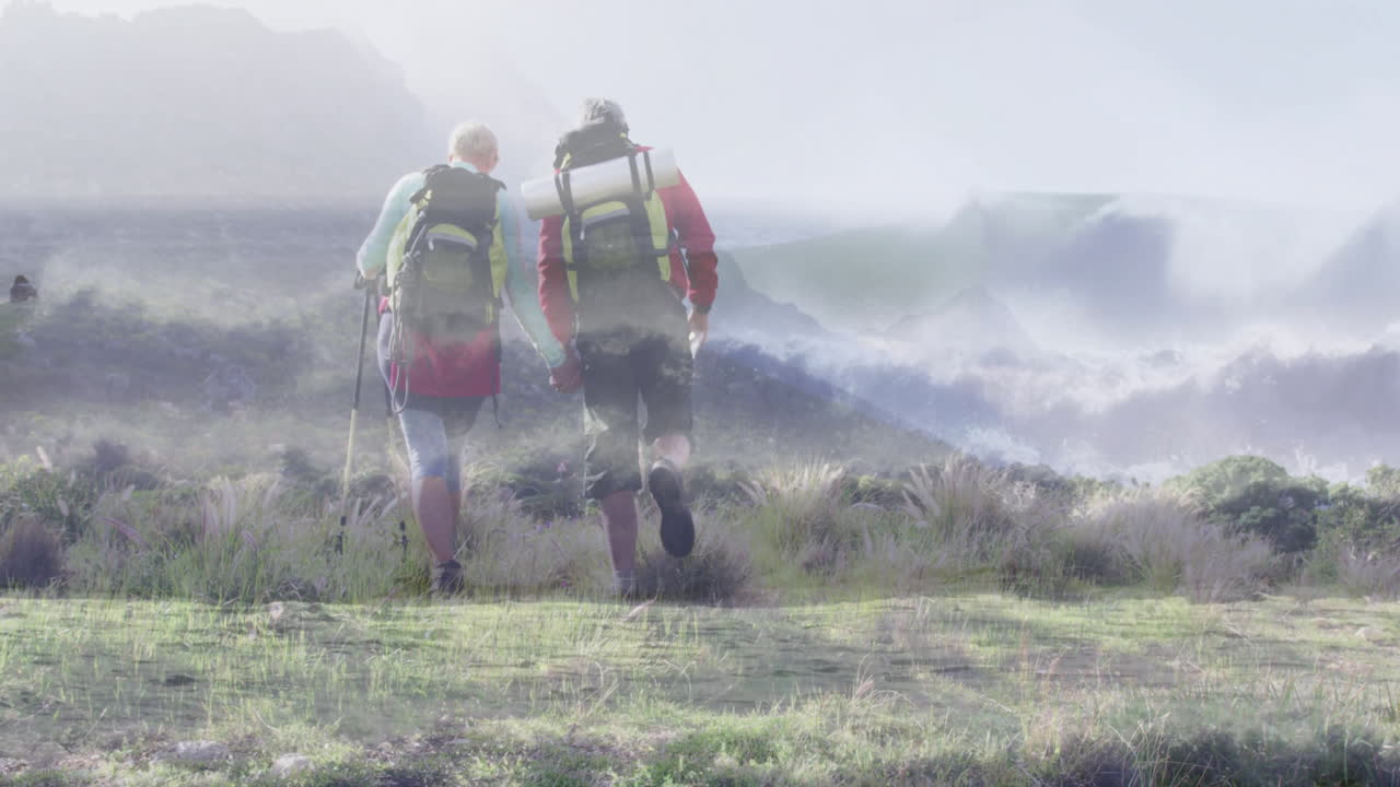 mature couple hiking through misty hills, showing floating heart rate icon and step count