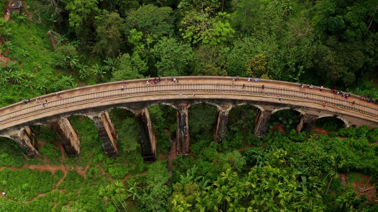 Vista aerea con drone del Ponte dei Nove Archi a Ella, Sri Lanka, circondato da una giungla lussureggiante, montagne e paesaggi tropicali nebbiosi.