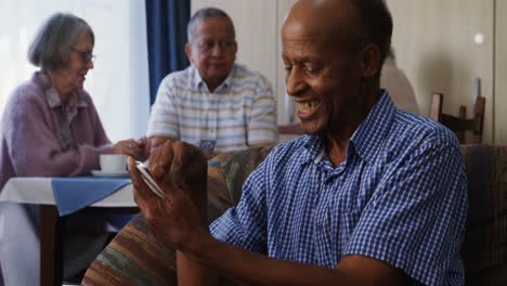 Senior-man-using-mobile-phone-with-his-friends-sitting-in-background-4k