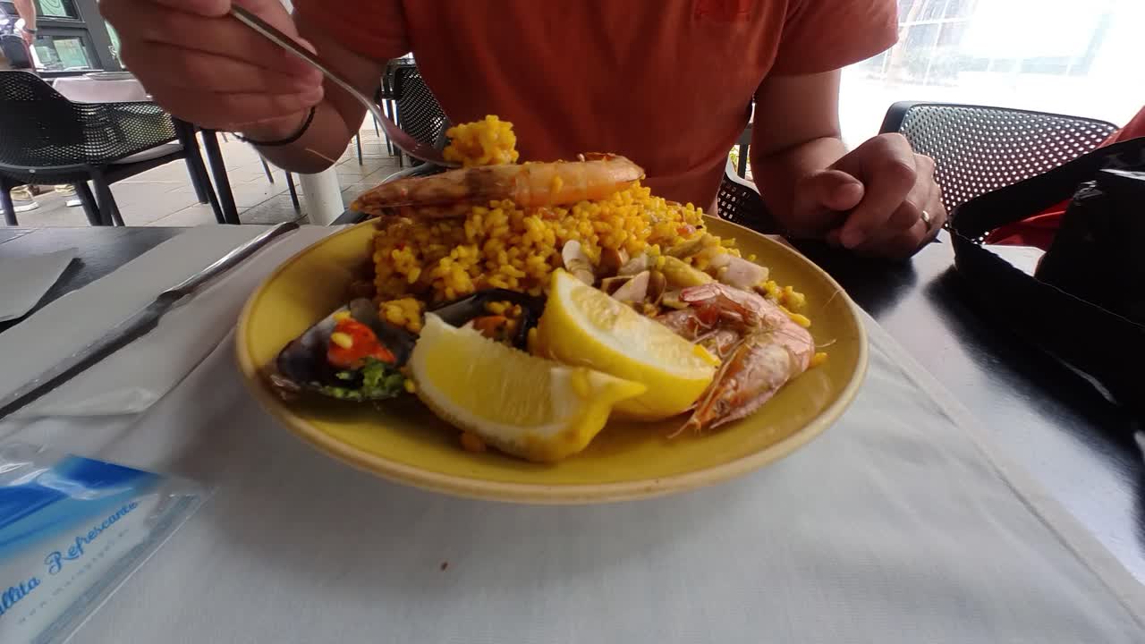 hombre comiendo paella en un restaurante en tenerife, españa, mariscos, arroz, limón