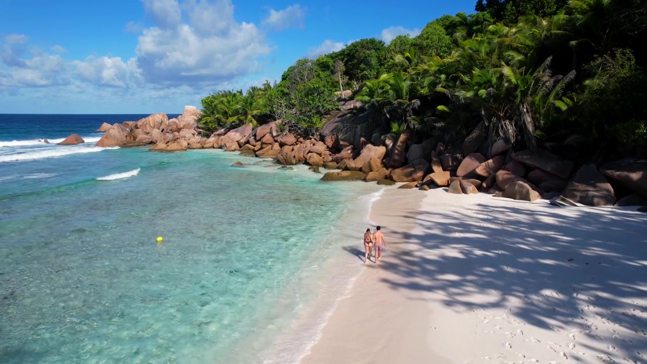 Giovane coppia che cammina insieme su una spiaggia tropicale delle Seychelles. Vista aerea