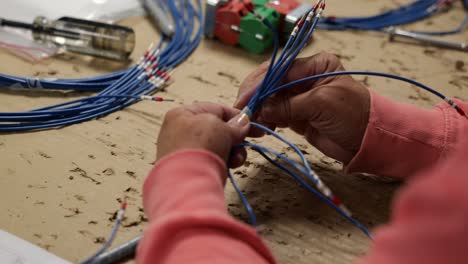 a person working at a table wrapping and coiling wires